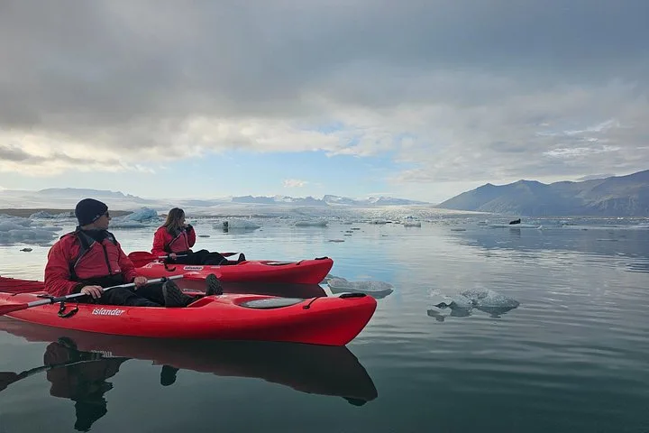 Kayaker and glacier hikers by the ice on a Jökulsárlón glacier lagoon boat tour in South East Iceland